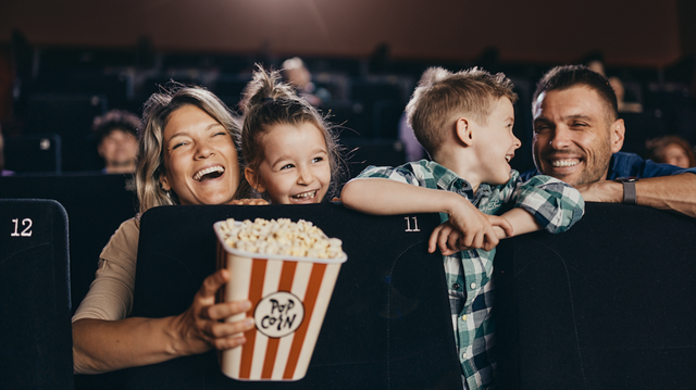 Cheerful family having fun while watching a funny movie in cinema.